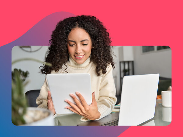 Frau mit dunklen Locken sucht nach Jobs am Tablet im Home Office
