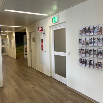 Fluransicht zum Notausgang mit Beschilderung und Broschüren an der Wand