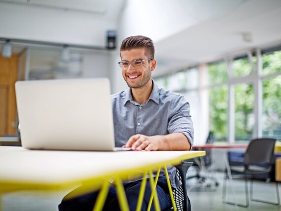 Ein Mann arbeitet fröhlich an seinem Laptop.