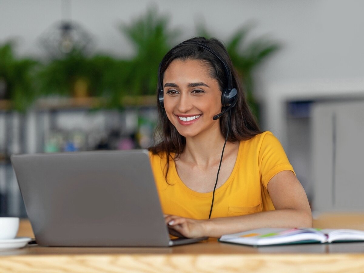 Eine Frau mit Headset sitzt vor ihrem Laptop.