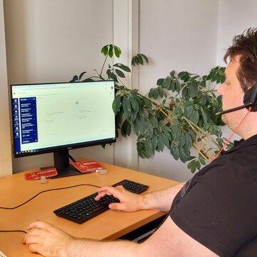 Ein Teilnehmer sitzt an seinem Arbeitsplatz und trägt ihr Headset während er in der virtuellen Lernumgebung lernt.