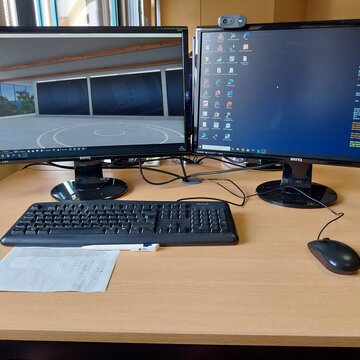 PC-Arbeitsplatz mit zwei Monitoren, Tastatur, Maus, Webcam und Headset.