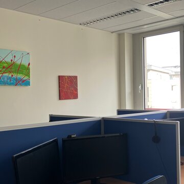 Abgetrennter Arbeitsbereich im Trainingsraum mit zwei Bildschirmen und zwei Bildern an der Wand
