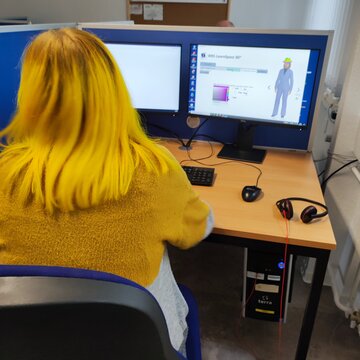 Teilnehmerin schaut auf ihren PC und lernt an zwei Bildschirmen.