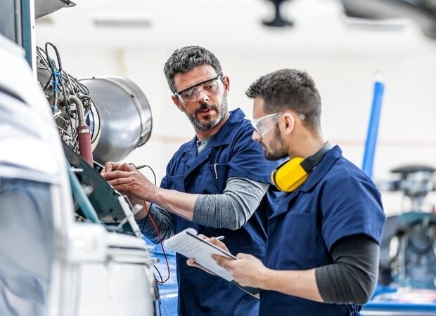 Zwei Männer in Schutzkleidung arbeiten an einer Maschine