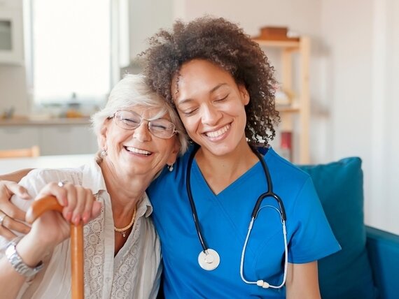 Eine junge Pflegerin umarmt eine Seniorin herzlich