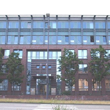 Außenansicht vom Gebäude, welches eine rot-braune Klinkerfassade und viele Fenster hat.
