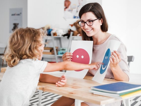 Eine junge Pädagogin macht Übungen mit einem Kleinkind