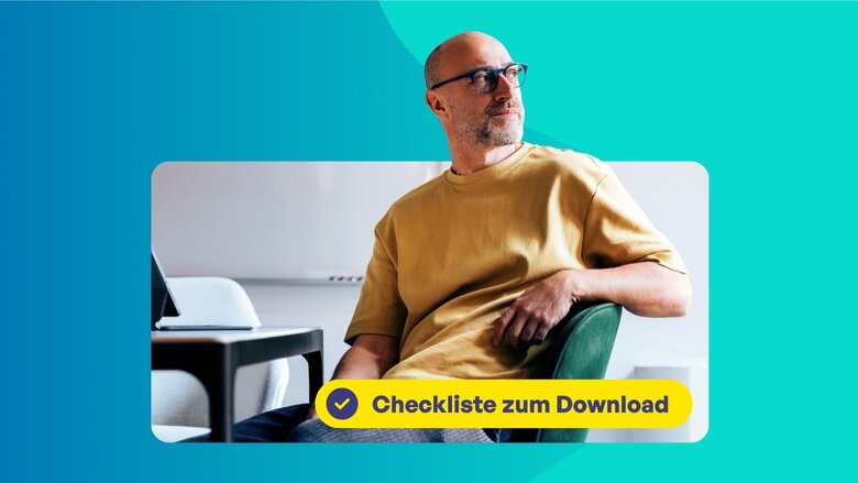 Mann mit Brille in gelbem T-Shirt sitzt auf einem Stuhl und schaut nachdenklich