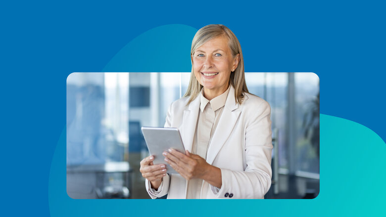 Frau mit grauen Haaren in Anzug hält Tablet in der Hand.