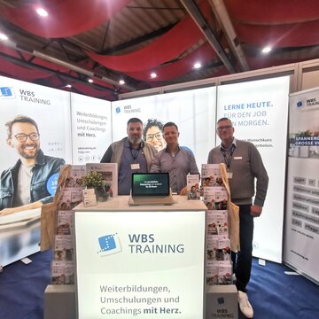 3 Mitarbeiter stehen en einem Messestand.