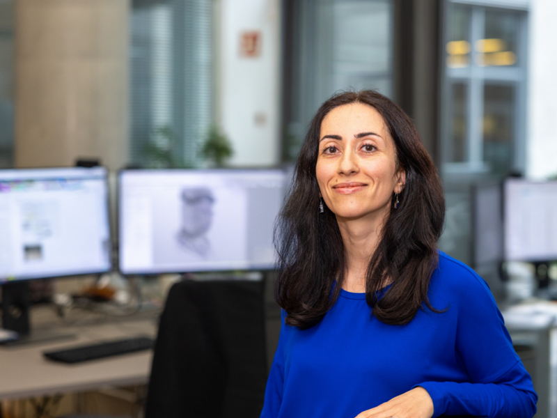 Frau mit schwarzen Haaren im Büro vor ihren Bildschirmen