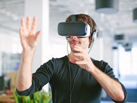 Ein junger Mann im Büro mit VR-Brille.
