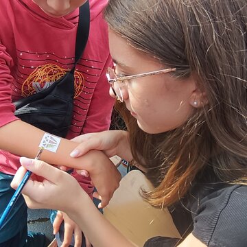 Schülerin malt ein Bild auf einen Kinderarm.