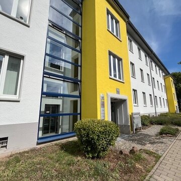 Außenansicht vom Gebäude der Einrichtung. Gelb, weiße Fassade. Sonniger Tag.
