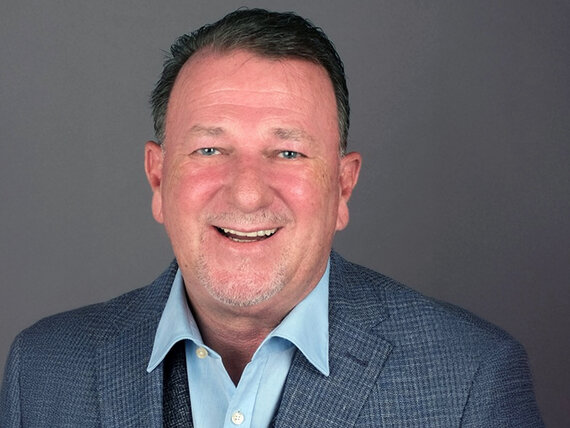 Mann mit grauem Sakko und hellblauem Hemd vor grauem Hintergrund
