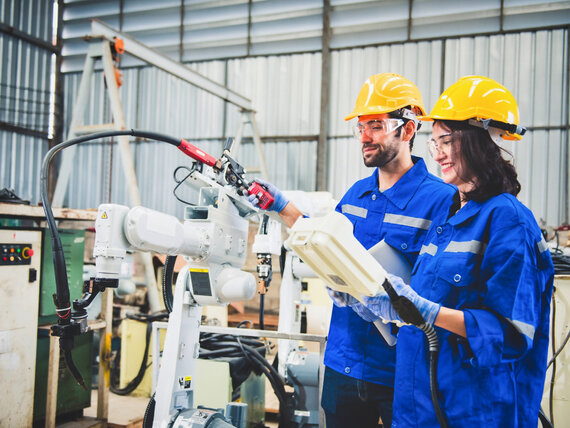 Eine Frau und ein Mann in Schutzkleidung arbeiten an einer modernen Schweißmaschine