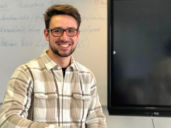 Junger Mann mit Brille in einem Schulungsraum.