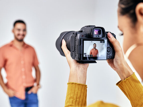 Eine Fotografin macht Bewerbungsfotos von einem jungen Mann.