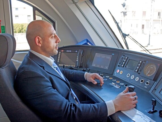 Ein Bahnfahrer sitzt im Cockpit eines Zuges und steuert diesen.