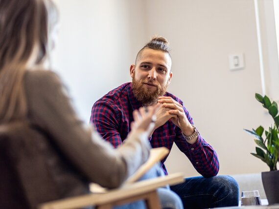 Ein junger Mann mit Bart in einer Therapiesitzung mit seiner Therapeutin