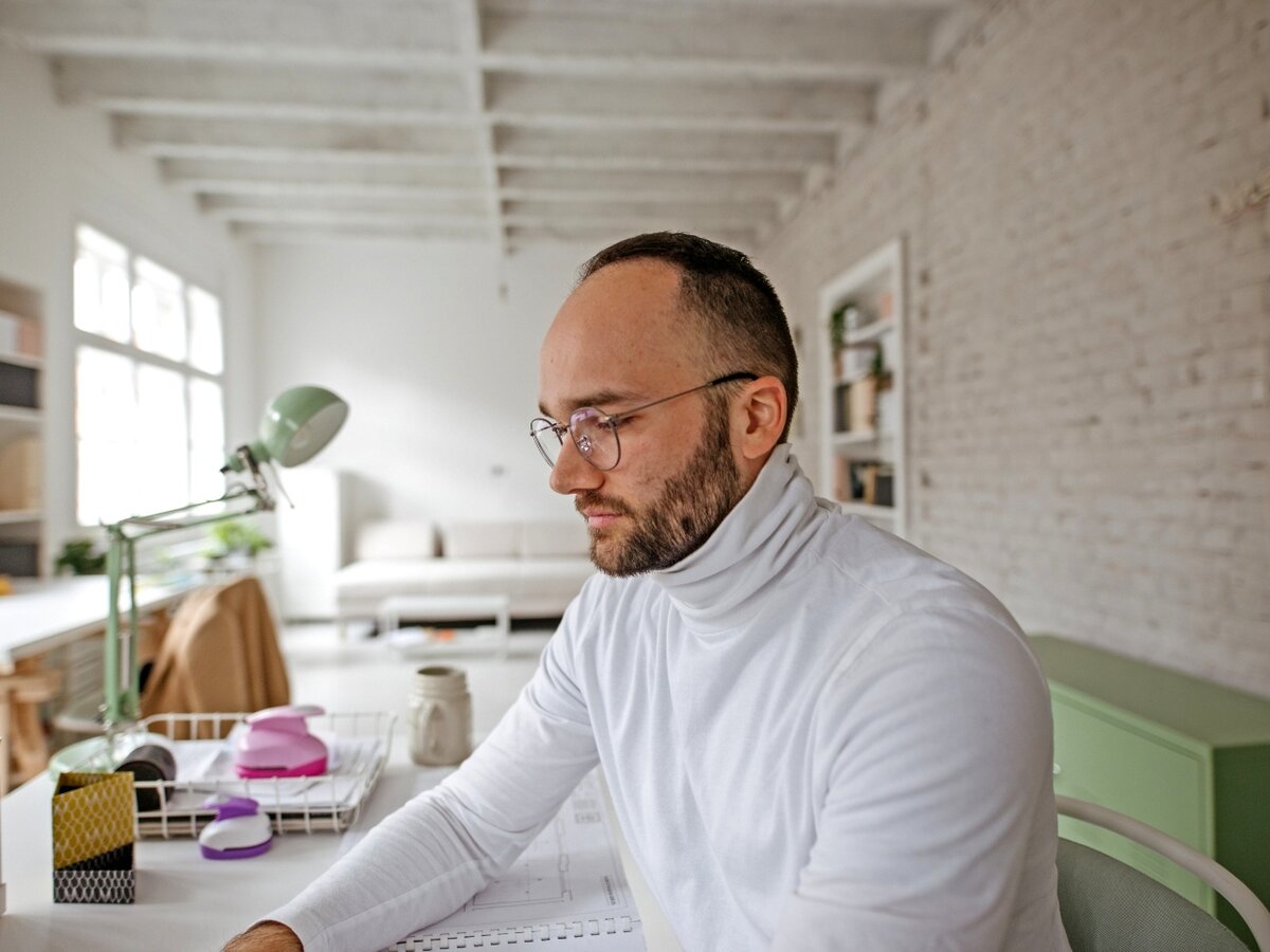 Ein Mann sitzt am Schreibtisch und hat eine Planzeichnung vor sich liegen.