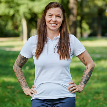 Vanessa Tonn steht im weißen T-Shirt mit WBS GRUPPE Logo in der grünen Natur und lächelt freundlich.