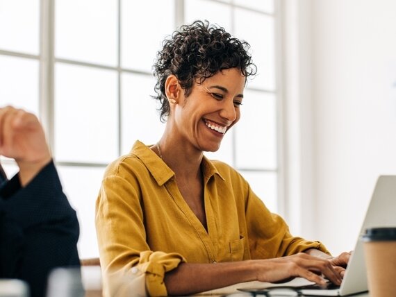 Zwei Frauen am Schreibtisch. Zwei Frauen sitzen an einem Schreibtisch und lachen fröhlich während der Arbeiit.