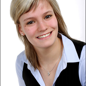 Portrait einer blonden Mitarbeiterin, die freundlich in die Kamera lächelt.
