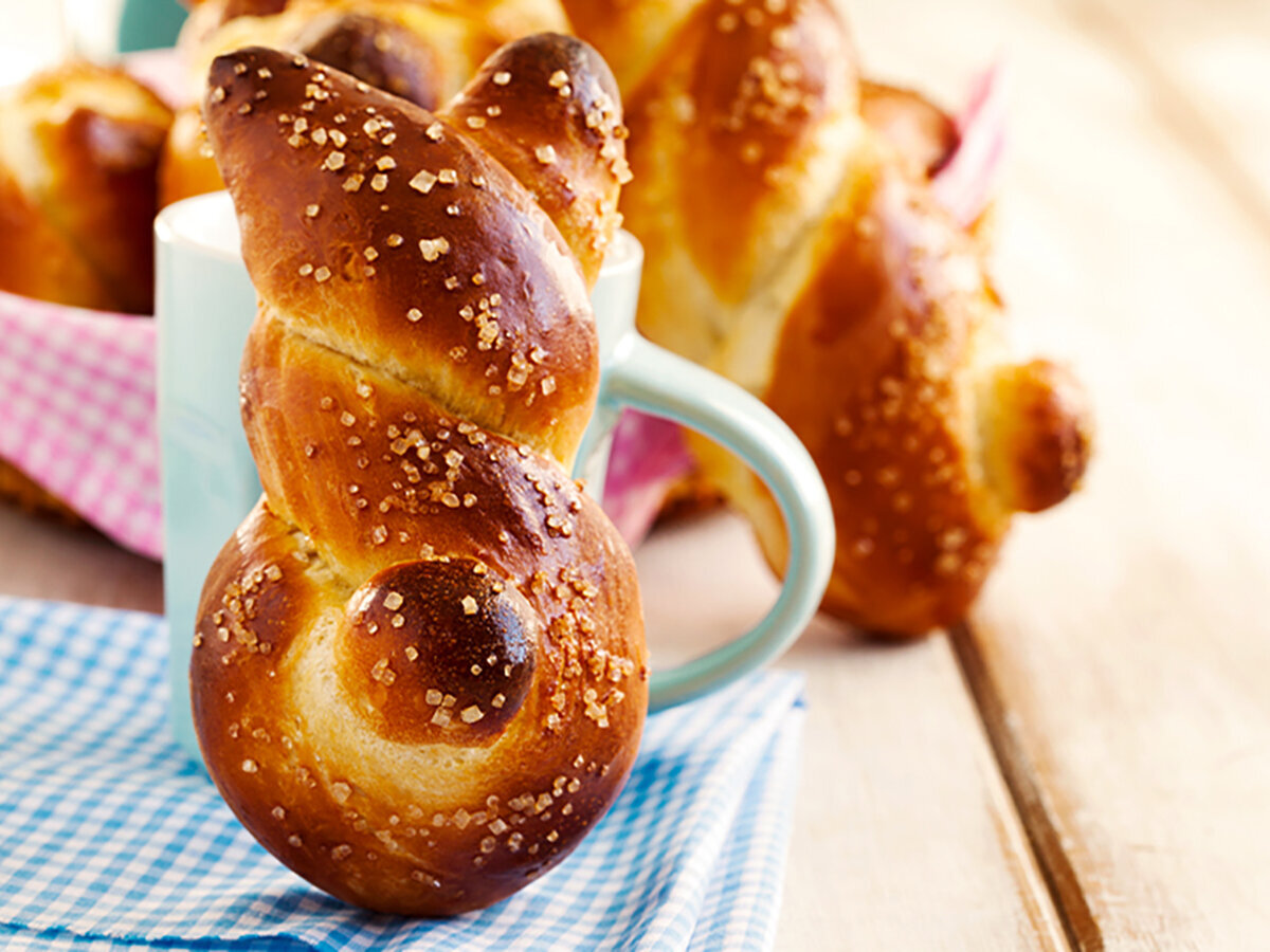 Osterrezept Hasenbrötchen ein frisch gebackenes Hasenbrötchen, an eine Tasse gelehnt.