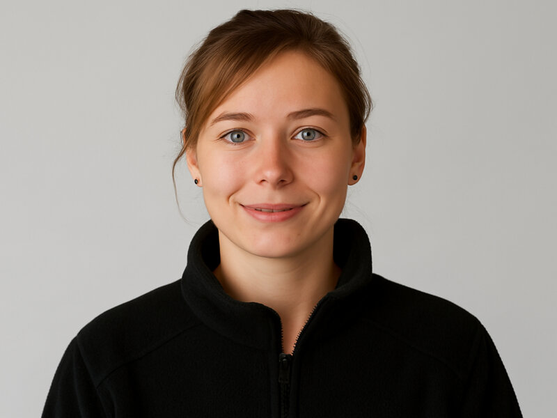 Porträt einer jungen Frau, die einen schwarzen Fleecepullover trägt und freundlich in die Kamera schaut.