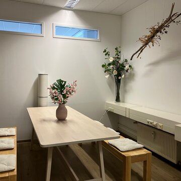 Pausenbereich mit zwei Sitzbänken an einem Tisch auf dem Blumen in einer Vase stehen