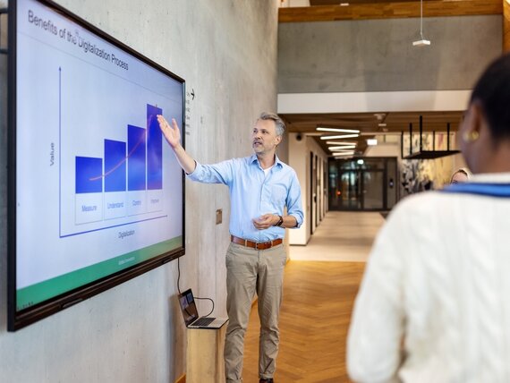 Ein Manager hält eine Präsentation an einem großen Screen im Foyer einer Firma
