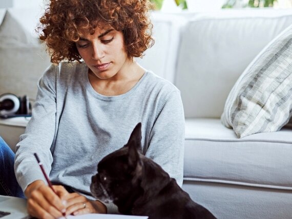 Eine Frau mit Hund arbeitet an ihrem Laptop.