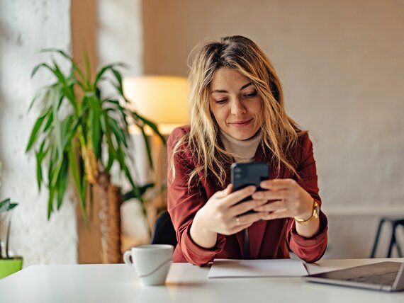 Eine Frau im Homeoffice bedient ihr Smartphone.
