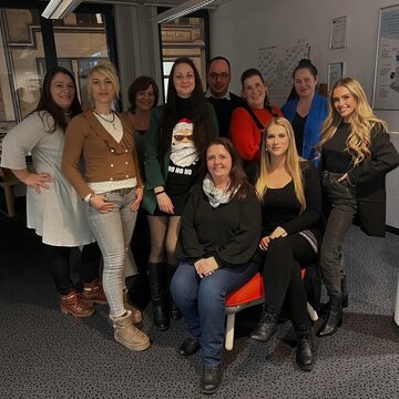 Gruppenfoto Team Altenburg, 10 freundliche Personen, zum Teil stehend, zum Teil sitzend.