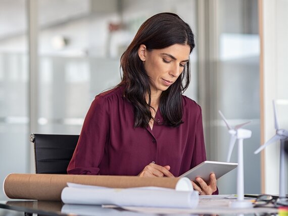 Eine Frau im Büro mit Windrad Modellen schaut auf ihr Tablet.