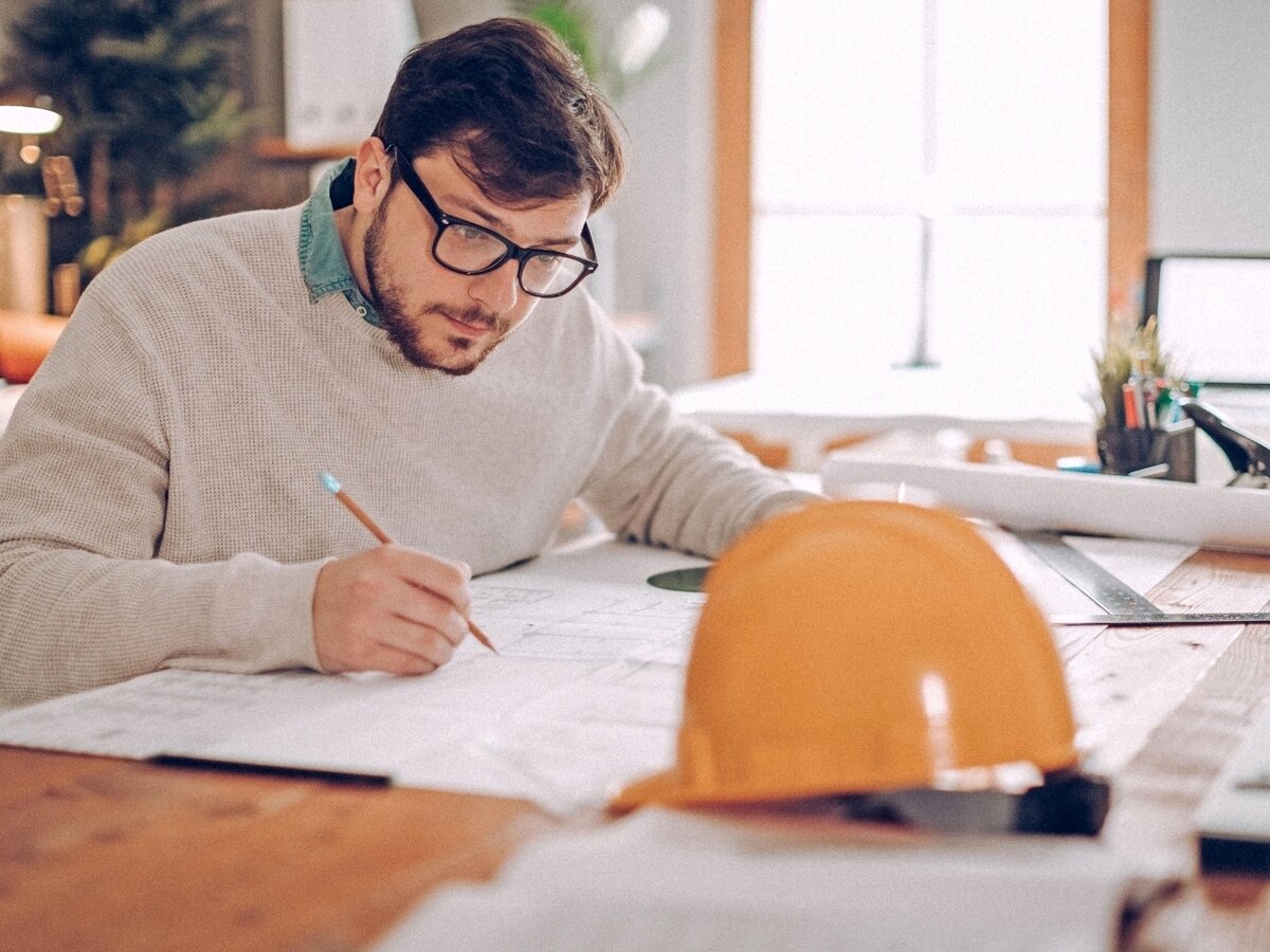 Bauingenieur mit Planzeichnungen. Ein Bauingenieur arbeitet an seinen Planzeichnungen.