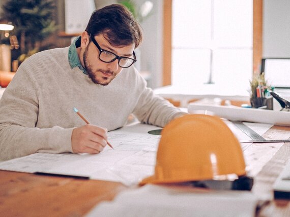 Ein Bauingenieur arbeitet an seinen Planzeichnungen.