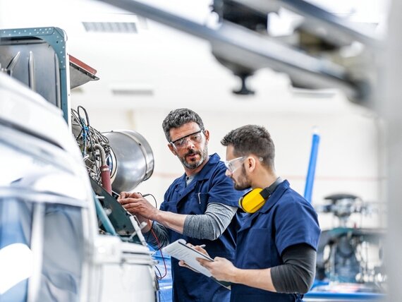Zwei Männer in Schutzkleidung arbeiten an einer Maschine
