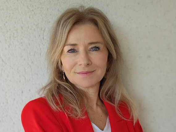 Eine Frau mit langen blonden Haaren und einem roten Sakko.