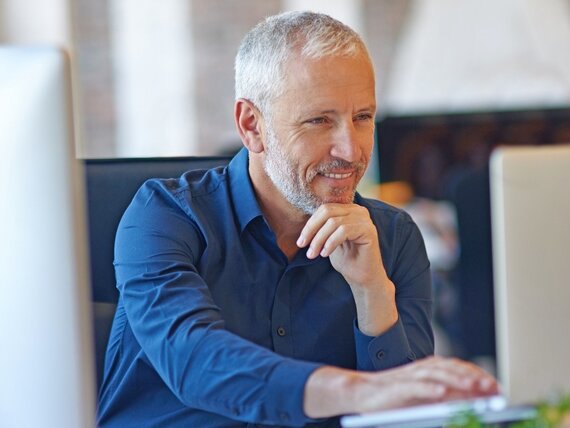 Ein fröhlicher Mann sitzt am Laptop