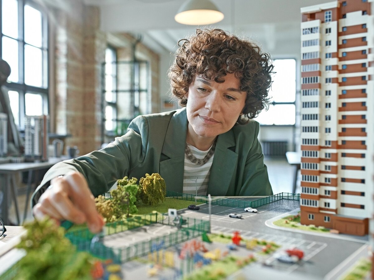 Frau mit Modellstadt. Eine Frau arbeitet an einer Modellstadt.