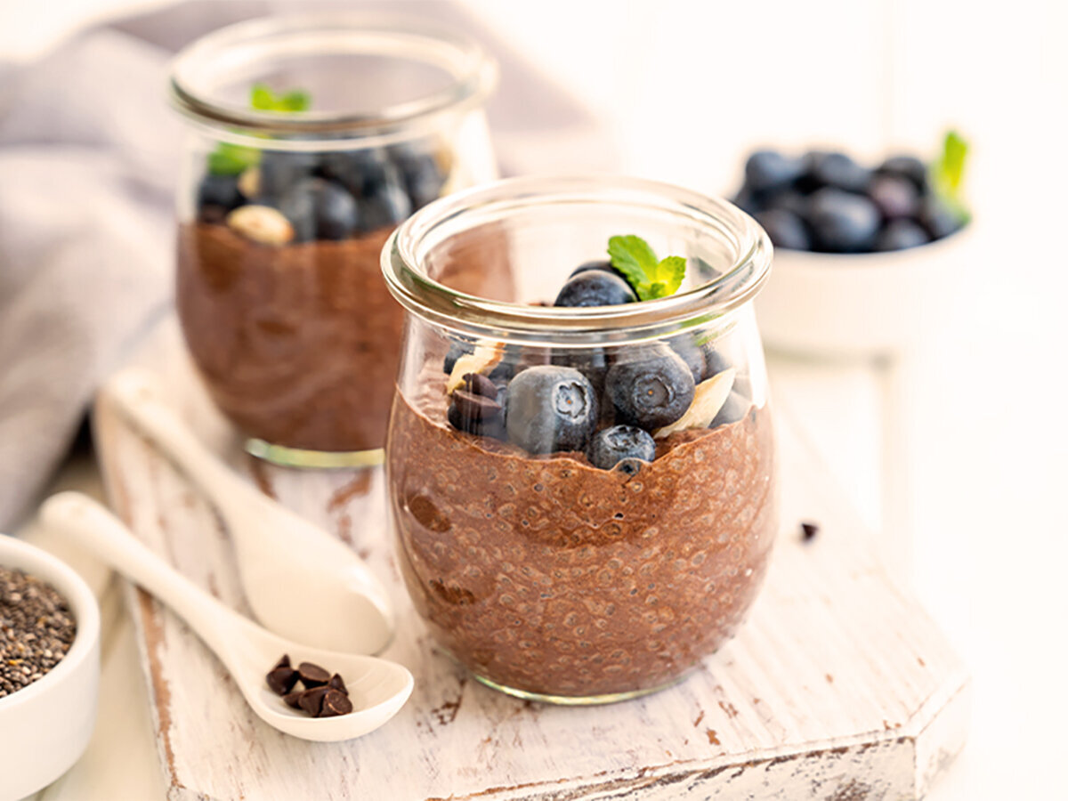 Osterrezept Chia-Pudding Zwei Dessertgläser, die mit Chia-Pudding und frischen Heidelbeeren gefüllt sind.