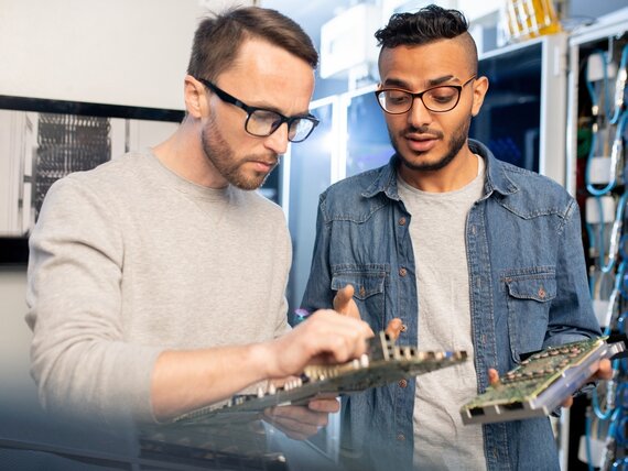 2 Männer arbeiten an Computern und Servern.