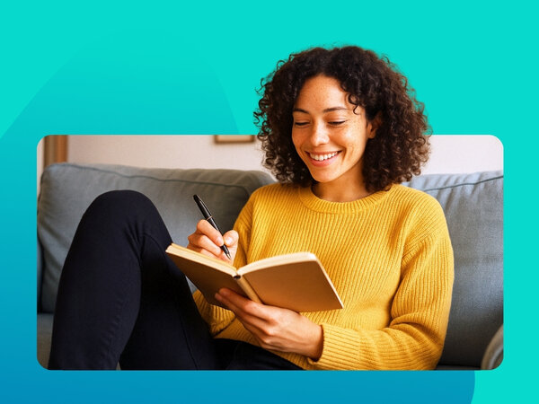 Frau mit Notizbuch und Stift in der Hand sitzt auf der Couch