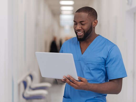 Ein Pfleger schaut sich etwas am Laptop an