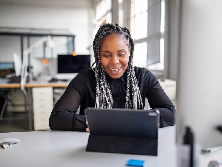 Eine Frau sitzt in einem Büro und arbeitet an ihrem Tablet
