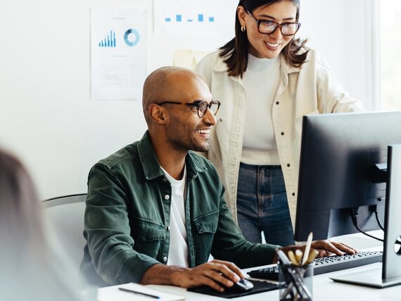 Eine Frau und ein Mann schauen sich etwas auf dem Computerbildschirm an.