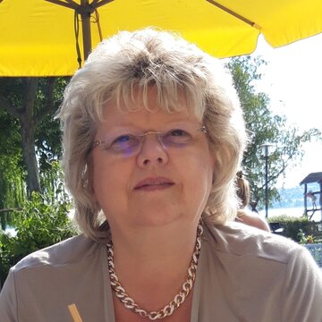 Eine Frau mit Brille und beigem Blazer